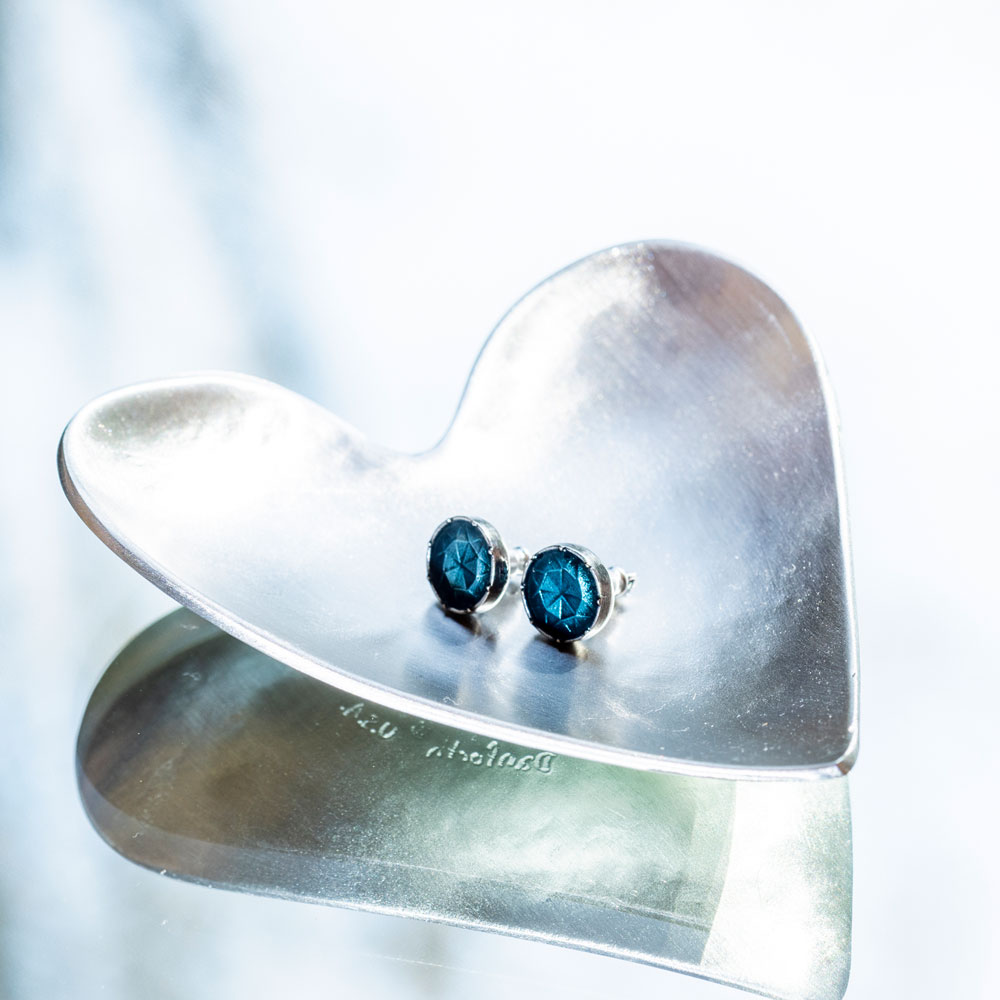 small green, gem-like earrings on a pewter heart-shaped tray