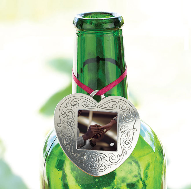 Pewter heart-shaped picture frame ornament hung over the neck of a wine bottle